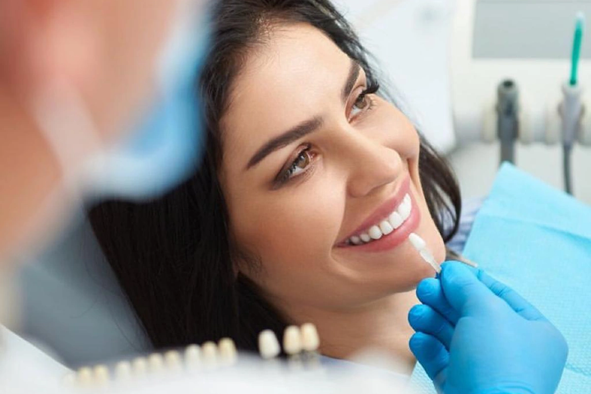 Stomatolog pregleda pacijentkinju i bira nijansu zuba pred implantološku terapiju u ordinaciji Branko Dental Tehno